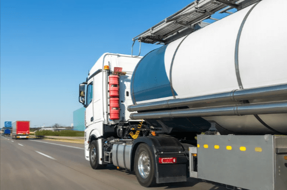 A white hazmat hauling truck on traveling on the road.